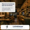 Restaurant met verlichte bar, hanglampen en sfeervol gedekte tafels.